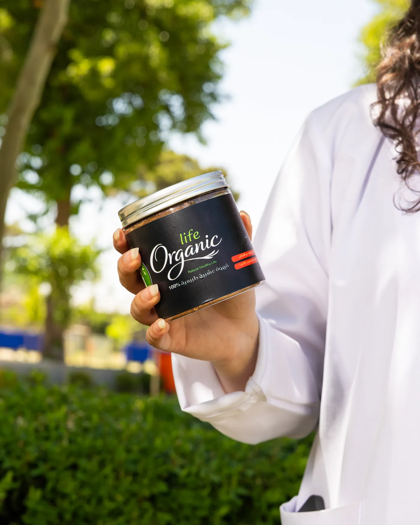صيدلانية بمعطف أبيض تحمل علبة قهوة Organic Life